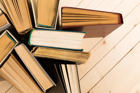 Stacked hardcover books on a wooden surface showing various spine colors and textures