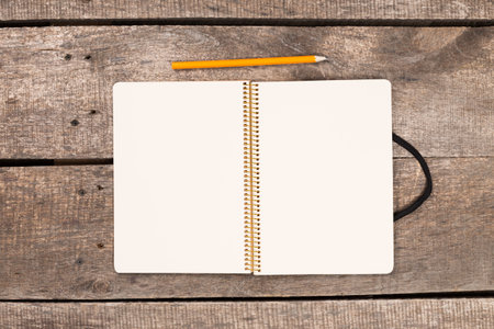 Blank notebook and pencil on wooden table ready for writing or drawing ideas