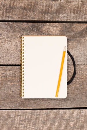 Open notebook with a yellow pencil resting on wooden surface