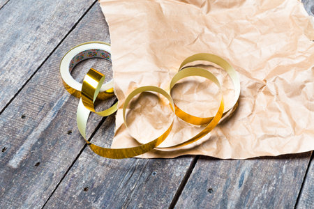 Crafting with golden tape on brown paper in a rustic wooden workspaceの写真素材