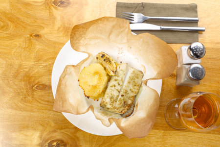 Grilled fish served with sides on a dish in a cozy dining setup at a restaurantの写真素材
