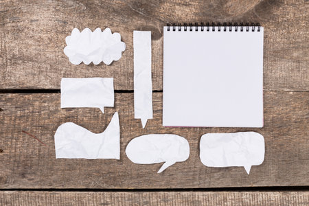 Paper cutouts and blank notepad on wooden surface for creative brainstorming and ideas