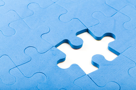 Puzzle piece missing from a blue jigsaw puzzle in a close-up viewの写真素材
