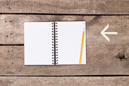 Open notebook with a pencil on a rustic wooden table during a quiet afternoon