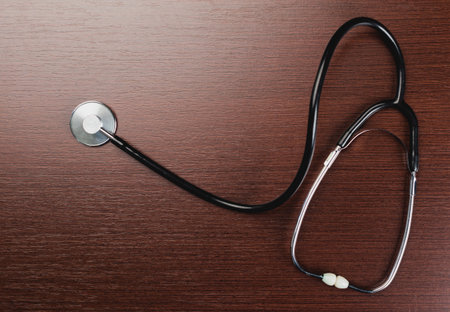 Stethoscope rests on wooden surface in medical setting during daytime examinationの写真素材