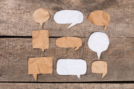 Crafty paper speech bubbles arranged on wooden surface for creative communication