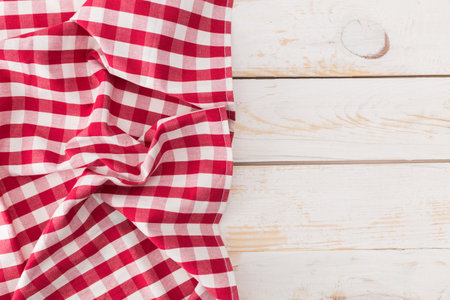 Red and white checkered tablecloth draped over a wooden surface in a casual setting
