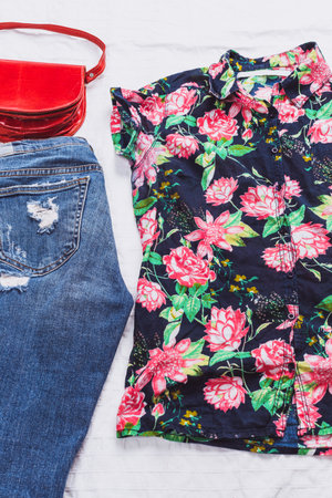 Stylish outfit arrangement featuring floral top and distressed jeans with a red handbag