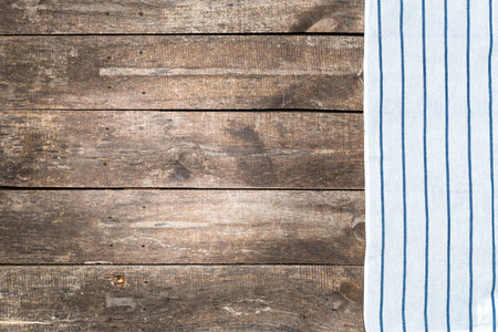Wooden table surface with a striped cloth on one side during daylight hours