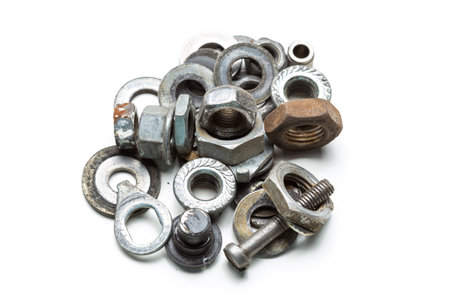 Various types of metal fasteners arranged in a mixed pile on a white surface