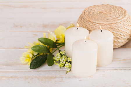 Calming atmosphere created by lit candles and flowers on rustic wooden surfaceの写真素材