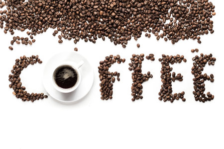 Freshly brewed coffee with beans arranged creatively on a white backgroundの写真素材