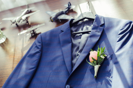 Elegant suit with boutonniere and vintage airplanes in background at a wedding venueの写真素材