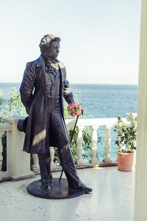 Statue of a man holding a cane near the ocean on a clear day in a scenic location