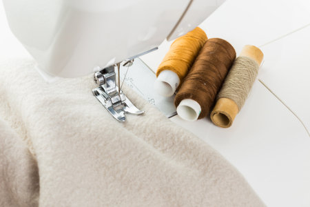 Sewing machine with spools of thread on fabric creates handmade textile project