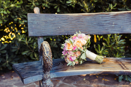 Bouquet placed on a rustic bench in a vibrant garden during a sunny dayの写真素材
