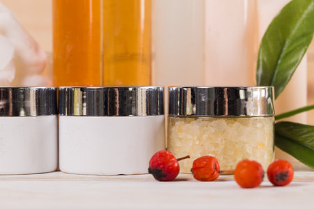 Natural skin care products arranged on a wooden surface with red berries and greenery