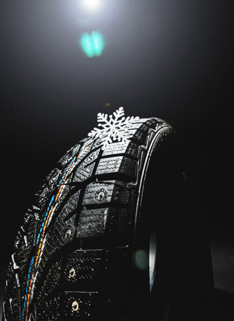 Winter tire showcasing tread design and snowflake emblem in studio lighting