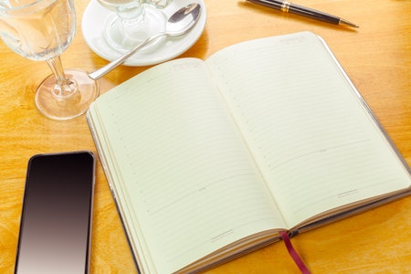 Notebook with blank pages and drinks on a wooden table in a cozy cafe setting