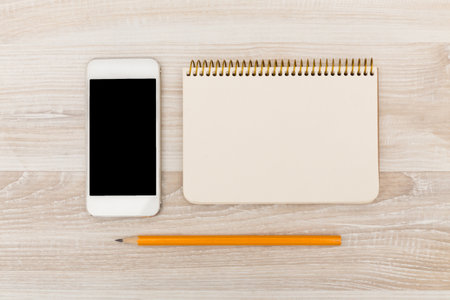 Notepad, smartphone, and pencil arranged on a wooden table for organization and planningの写真素材