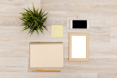 Creative workspace setup with stationery, a smartphone, and a tablet on a wooden deskの写真素材