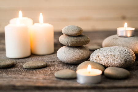 Calming arrangement of stones and candles on a wooden surface for relaxationの写真素材