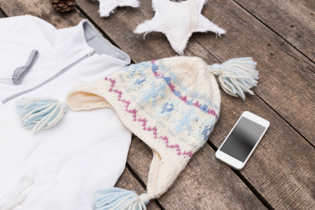 Warm winter accessories arranged on rustic wooden table with smartphone and starsの写真素材