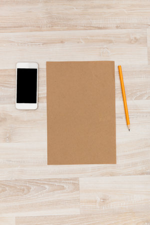 Workspace setup with blank paper, smartphone, and pencil in minimalistic settingの写真素材