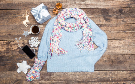 Cozy winter outfit laid out with gifts and seasonal decorations on wooden surface