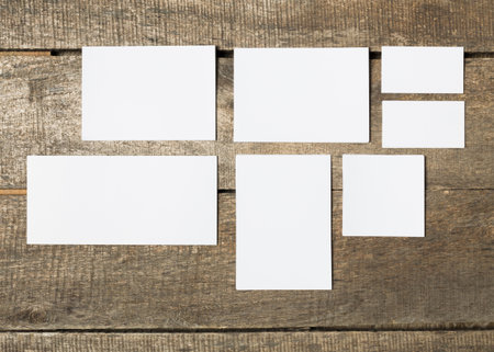 Various blank paper cards arranged on a wooden surface in different sizes and orientations