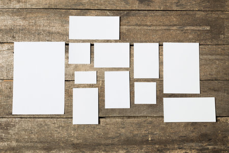 Collection of blank paper sheets arranged on rustic wooden surface for creative projects