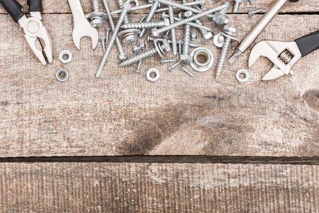 Tools and hardware scattered on a wooden surface in a workshop setting during the day
