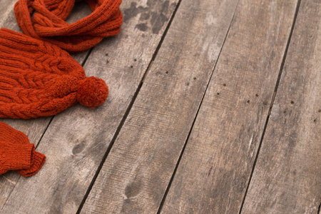 Cozy red accessories on a rustic wooden surface in a warm indoor settingの写真素材
