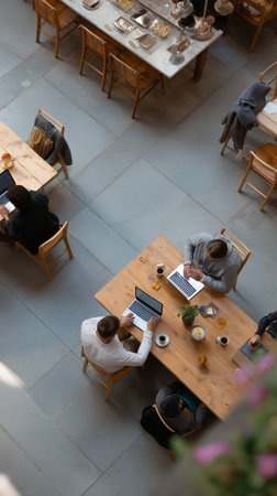 People working on laptops in a cozy cafe setting during the dayの素材