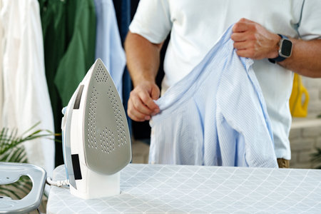 Ironing clothes in a well-lit laundry area with a relaxed atmosphere at homeの写真素材