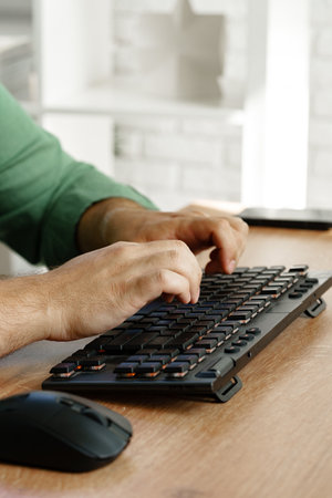 Hands typing on a keyboard beside a computer mouse during a work session at home