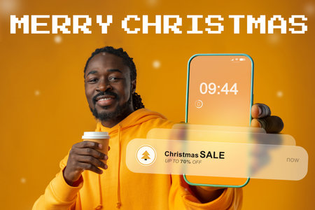 Christmas sale announcement with cheerful man holding phone and coffee in bright settingの写真素材