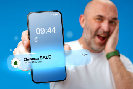 Excitement for Christmas sale promotion shared by a man with a smartphone in handの写真素材