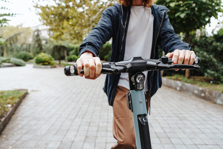 Person riding an electric scooter on a pathway surrounded by greenery at a parkの写真素材