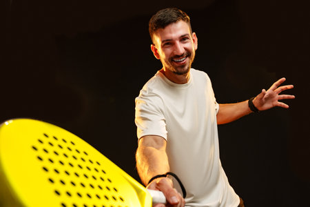 Man enjoying a fun moment playing pickleball with a bright paddle indoorsの写真素材