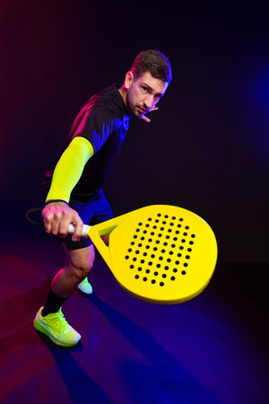 Sporting action with vibrant colors during a padel game at nightの写真素材