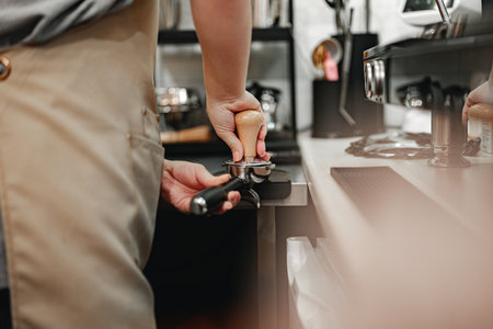 Barista preparing coffee with espresso machine in a busy cafe setting during afternoon hoursの写真素材