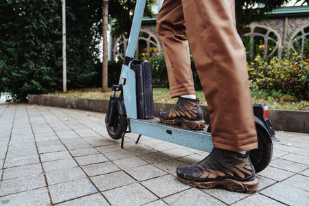 Person riding a scooter along a paved path in a garden area during the dayの写真素材