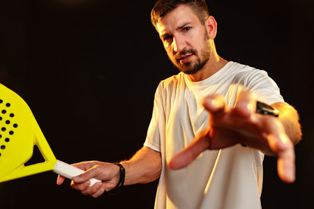 Male athlete in white shirt prepares for intense paddle sport competition indoors at night