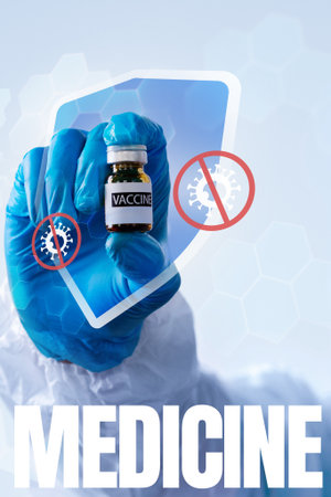 Hand holding vaccine vial with protective shield symbol against viruses in a medical settingの写真素材