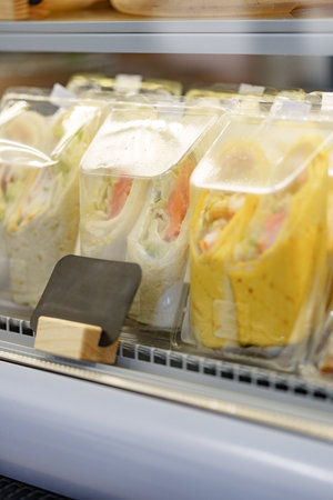 Fresh wraps displayed in a refrigerated case at a local food shop during middayの写真素材