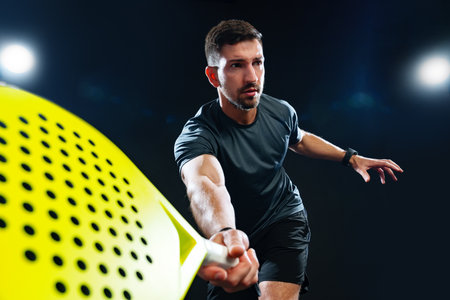 Serious athlete practicing paddle sports in a dark indoor facility with bright lightsの写真素材