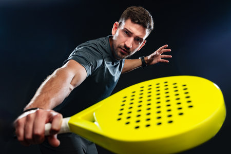 Man demonstrating pickleball skills with a yellow paddle in a dramatic setting