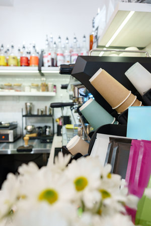 Coffee shop equipment and colorful cups on display with flowers in the foregroundの写真素材