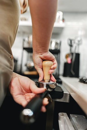 Barista preparing coffee by tamping espresso grounds in a cafe settingの写真素材